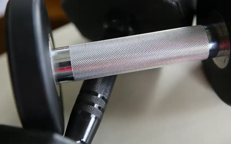 Close-up of a dumbbell handle showing knurling and rubber coating detail